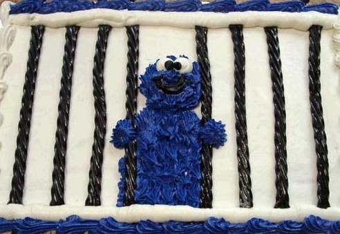 Cookie Monster character made of blue frosting behind black licorice bars on a white cake