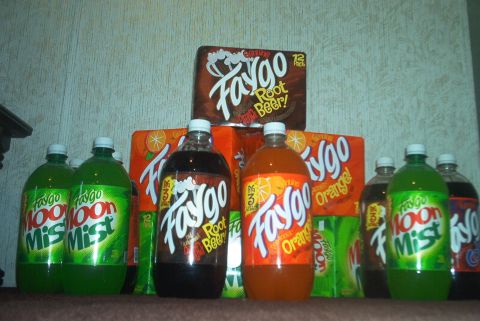 1985 Ford Crown Victoria LTD - A collection of Faygo brand soda bottles and cases, including Root Beer, Orange, and Moon Mist flavors.