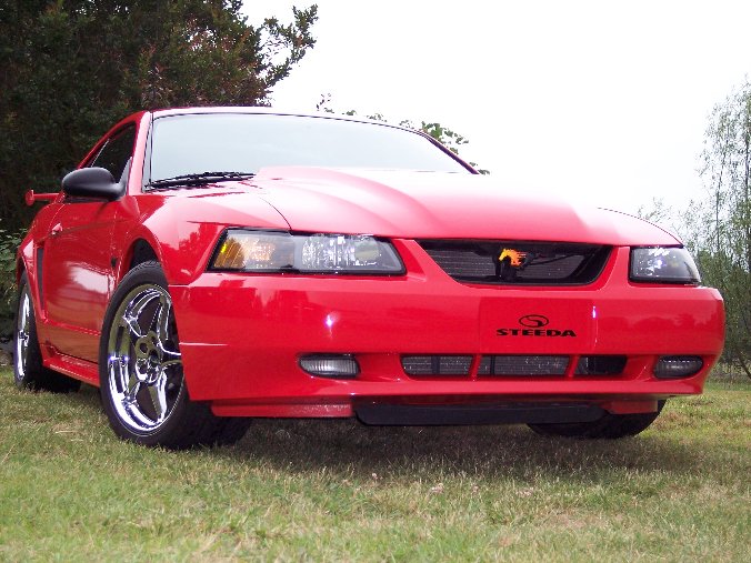 Low-angle view of a bright red New Edge Ford Mustang coupe with a Steeda bumper decal and chrome wheels