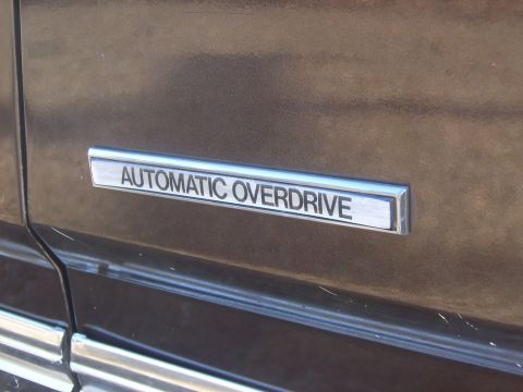 1982 Ford Crown Victoria LTD - Close-up of the 'Automatic Overdrive' badge on the side of a brown vehicle.