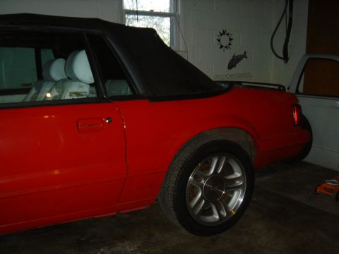 1986 Ford Mustang - Side view of a red 1986 Ford Mustang convertible with its black top up.