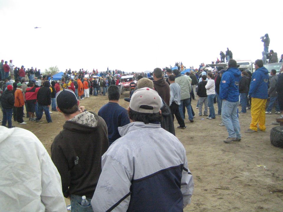 Off-road race car passing a crowd on a dirt desert course