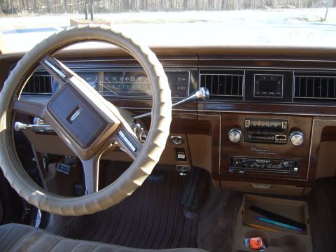 1982 Ford Crown Victoria LTD - The dashboard features a prominent steering wheel and an analog speedometer, with woodgrain accents and a vintage radio.