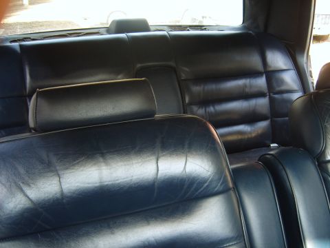 1982 Ford LTD Crown Victoria - Interior shot of a car's rear bench seat in dark blue/black vinyl, viewed over the folded front seatbacks, with a pillow-top headrest and p…