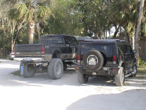 1993 Ford C-350 (Centurion Conversions) - Two modified vehicles, a lifted pickup truck and an SUV, are parked outdoors.