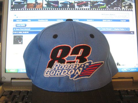 1990 Ford Bronco - blue and black baseball cap embroidered with the number 83 and a Robby Gordon logo rests in front of an open laptop displaying a web forum.