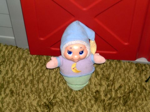 2006 Ford F1 - A toy doll sits on a carpeted floor in front of a red object.