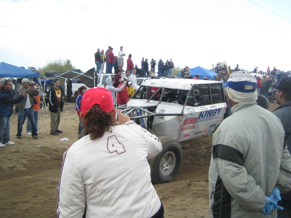 White off-road race buggy with Kirby sponsor decals on a sandy course