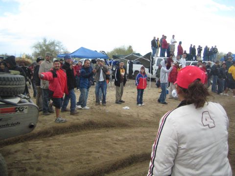 1990 Ford Bronco - Spectators stand on a sandy berm near a tube-frame buggy, its tire showing BFGoodrich and K&N markings.