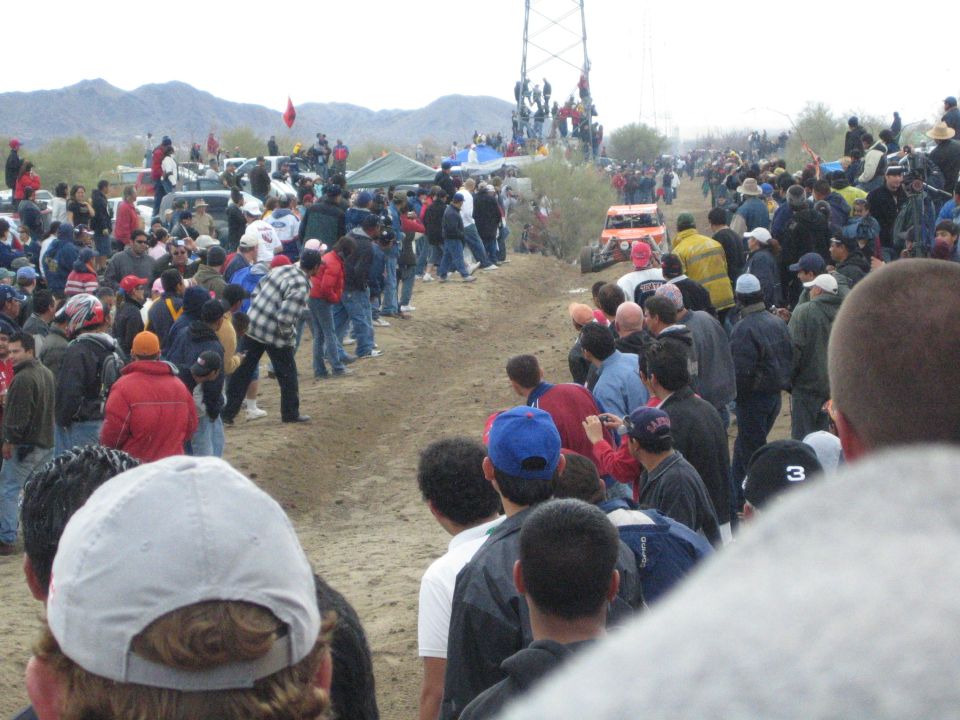 Crowd watching an off-road buggy on a dirt desert course