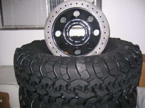 1978 Ford Bronco - A close-up view of a brake rotor resting on a stack of large off-road tires.