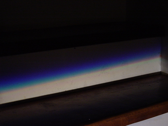 Blurry surface with rainbow light diffraction against dark background