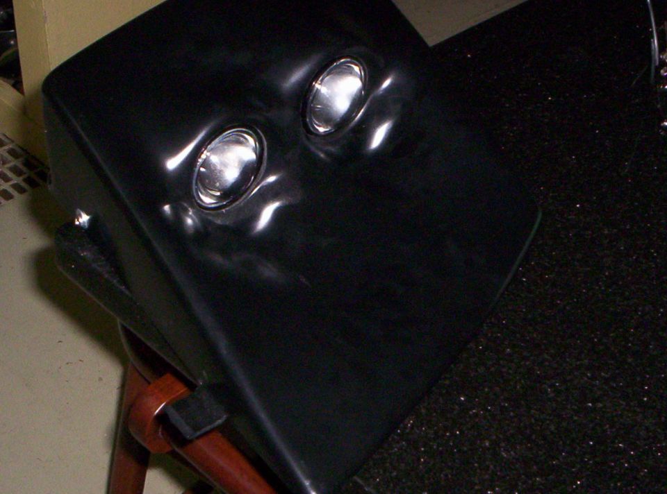 Glossy black housing with two clear projector lenses on a stand