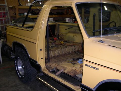 1982 Ford Bronco - Interior of a 1982 Ford Bronco stripped for work, showing rust and tools on the floor.