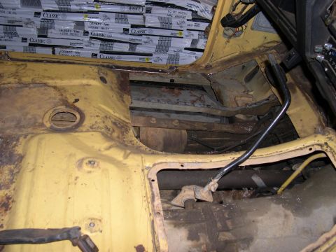1982 Ford Bronco - The interior of a yellow vehicle shows significant rust and exposed metal, indicating a state of disrepair.