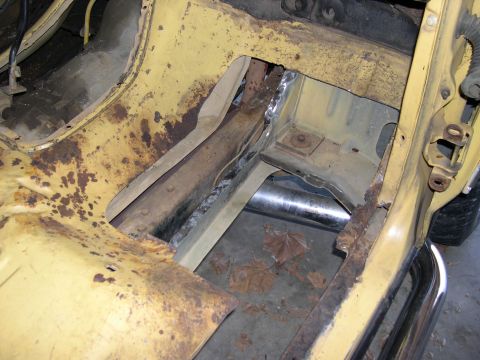 1982 Ford Bronco - This image shows the rusted chassis of a yellow vehicle, with exposed metal and structural components visible.