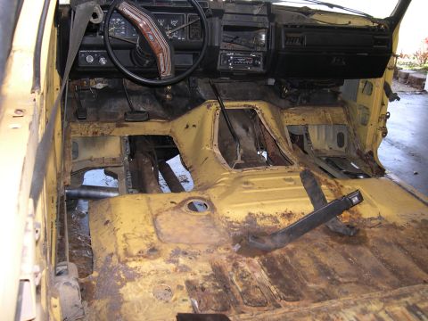 1982 Ford Bronco - The interior of this vehicle shows significant rust damage and missing components, indicating a state of disrepair.