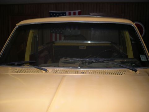 1982 Ford Bronco - The front of a yellow SUV is shown, with an American flag hanging in the garage behind it.