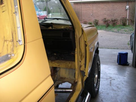 1982 Ford Bronco - Interior view of a yellow SUV, revealing its worn condition and a glimpse of the exterior through the open door.