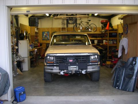 1982 Ford Bronco - A tan 1982 Ford Bronco with a winch and KC lights is parked inside a garage.