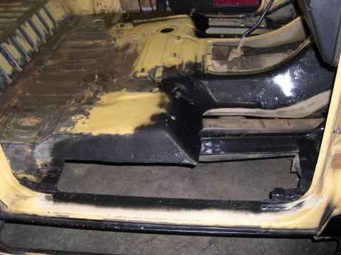 1982 Ford Bronco - Vehicle floor pan interior with rust damage and black coating visible.