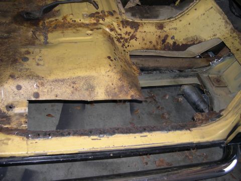 1982 Ford Bronco - The interior floor pan of a 1982 Ford Bronco shows extensive rust and damage, indicating a need for restoration.