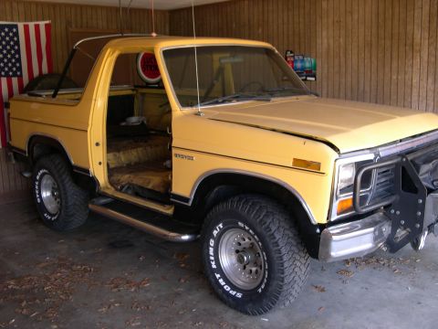 1982 Ford Bronco - 1982 Ford Bronco with its doors open, parked inside a garage.