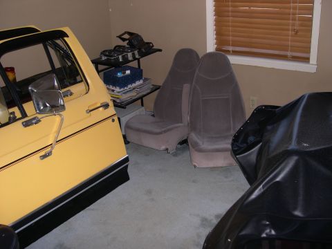 1982 Ford Bronco - Interior parts of a vehicle are stored in a room, including seats and a door.