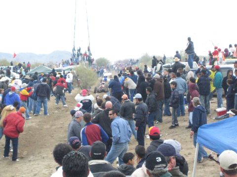 1990 Ford Bronco - large crowd fills a dirt desert race course as people watch from a tall tower structure under overcast skies.