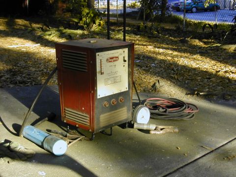 1993 Ford Bronco - A worn red Dayton AC arc welding machine set up on a concrete driveway with coiled red and black leads, an electrode holder, ground clamp,…