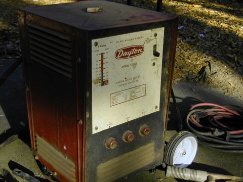 1993 Ford Bronco - A weathered red and black Dayton Model 3Z350 AC arc welding machine sitting on a concrete pad outdoors, with coiled red and black welding l…