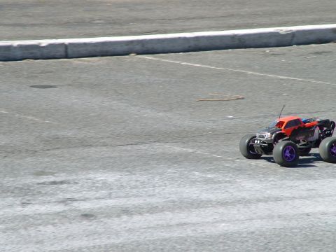 1994 Ford Bronco - A remote control monster truck with an orange body and purple wheels is seen on an asphalt surface.