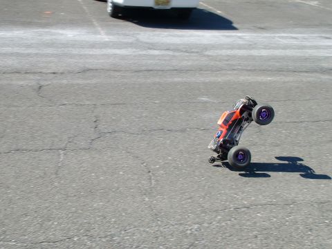 1994 Ford Bronco - A remote control car performs a wheelie on asphalt, with another vehicle partially visible in the background.