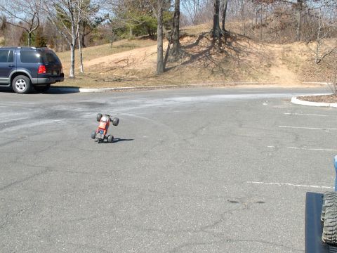 1994 Ford Bronco - A remote control car is seen on a paved surface next to a parked SUV.