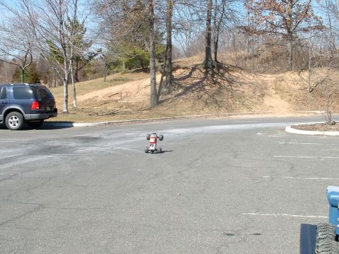 1994 Ford Bronco - A remote control car is on the pavement with a parked SUV in the background.