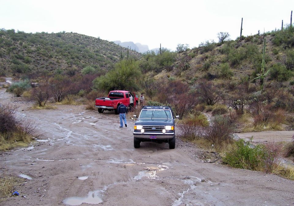 Dark blue 1992 Ford F-150 pickup and red Ford F-250 pickup on a dirt road