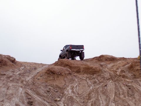 1991 Ford Bronco - Off-road pickup truck navigates a challenging dirt incline.