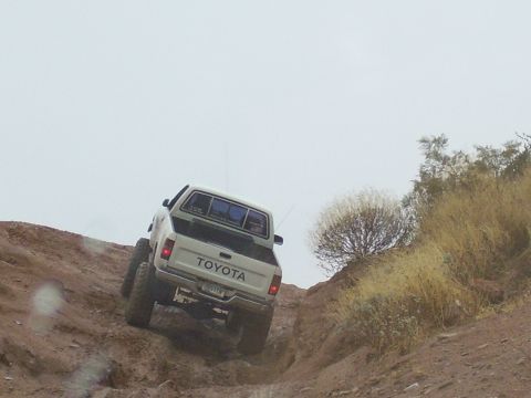 1991 Ford Bronco - This Toyota pickup truck is navigating a challenging off-road trail on a cloudy day.
