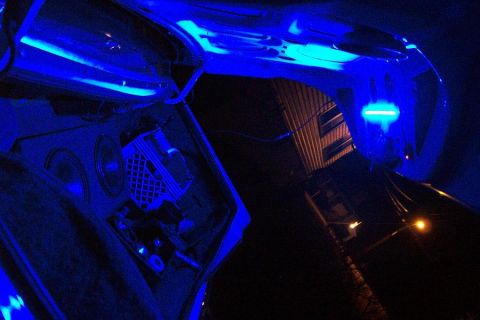 1985 Ford Crown Victoria LTD - The interior of a car trunk is illuminated by blue LED lights, highlighting audio equipment and speakers.