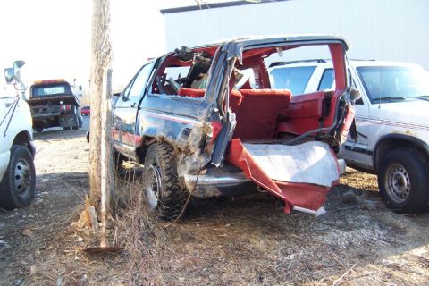 1977 Ford F-150 - A heavily damaged SUV sits in a lot next to another vehicle.