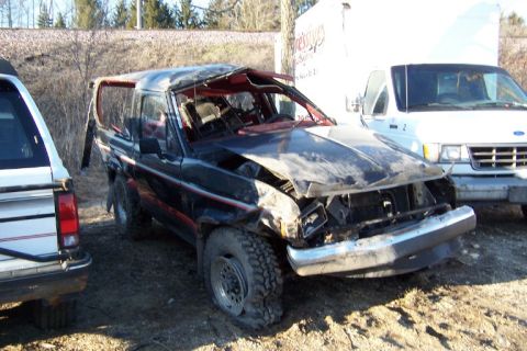 1977 Ford F-150 - This heavily damaged SUV sits next to other vehicles in an outdoor lot.