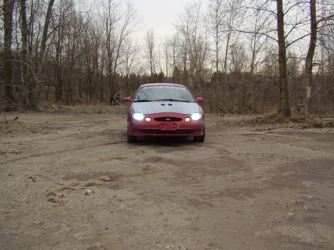 1997 Ford Taurus - Front view of a 1997 Ford Taurus with a silver hood and red body, parked outdoors.