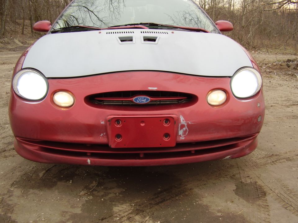 Front view of red Ford Taurus with hood up showing oval grille emblem
