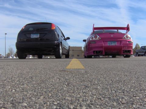 2002 Ford Focus - Rear view of a black 2002 Ford Focus and a pink Mitsubishi Eclipse parked on asphalt.