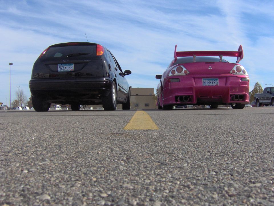 2002 Ford Focus and a pink Mitsubishi Eclipse parked side-by-side, rear view