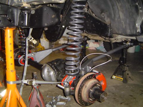 1989 Ford Bronco - Vehicle's front axle and suspension components are visible, supported by jack stands during work.