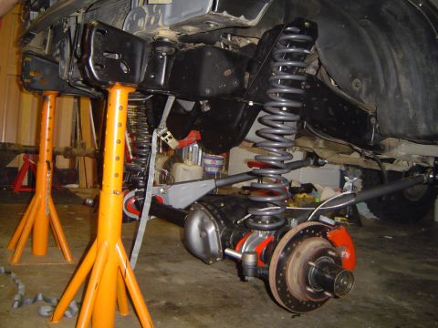 1989 Ford Bronco - Close-up of a vehicle's axle and suspension system being worked on, supported by jack stands.