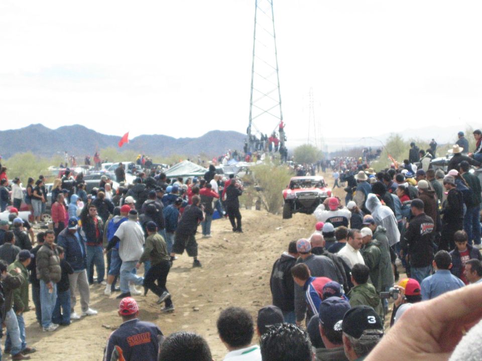 Large crowd watching off-road race truck on desert dirt road