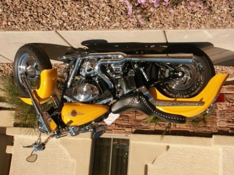 1985 Ford LTD Crown Victoria - A yellow motorcycle with a chrome engine and black seat is parked outdoors on a sunny day.