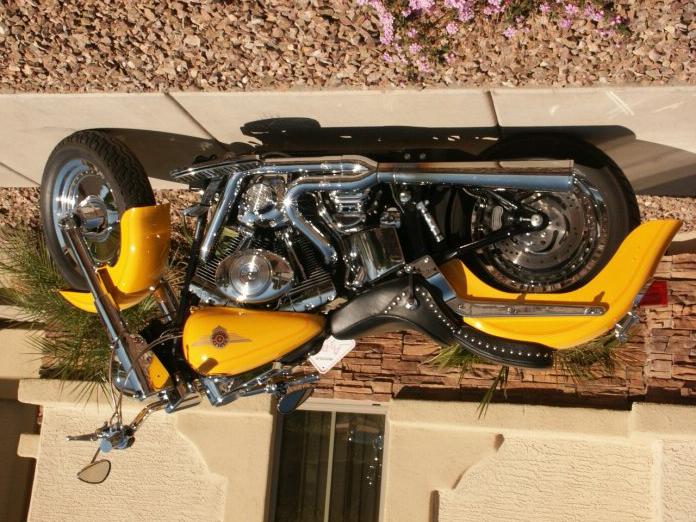 yellow motorcycle with chrome engine and black studded seat parked outside